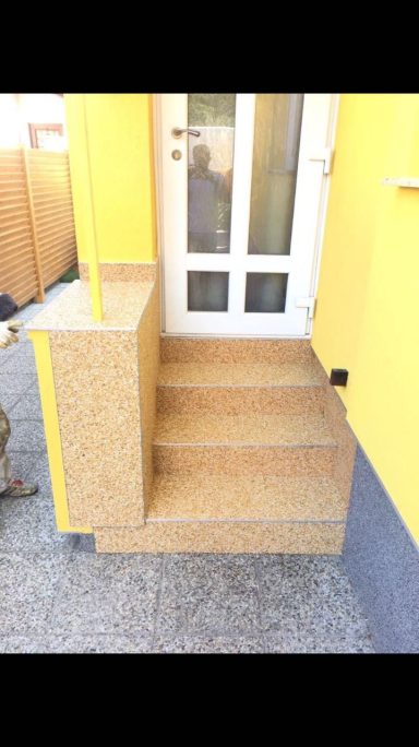 Treppen aus hellem Material mit gelber Wand im Hintergrund.